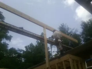 Carpenter setting a ridge beam over a new addition frame — Ice Dam Removal by Roofing Brothers in Winooski