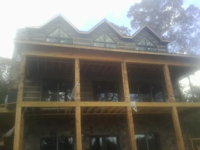 Dormers and porch framing on a large log home under construction — Roof Coating work by our crew in Winooski
