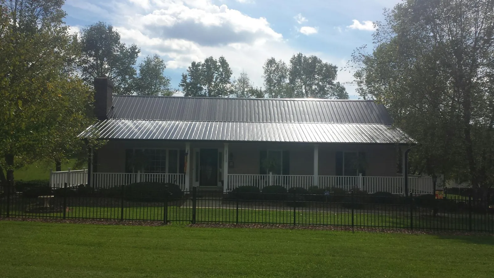 Gray metal roof on a brick ranch with a full width front porch — Gutter Guard Installation work by our crew in Winooski