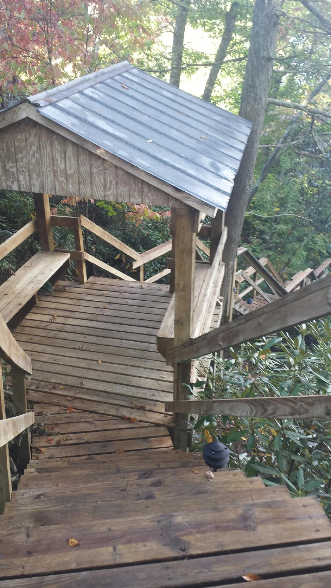 Metal roofed shelter over wooden steps on a wooded walkway — Skylight Repair & Installation work by our crew in Winooski