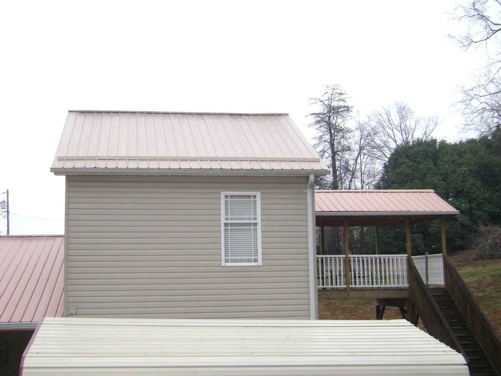 Tan metal roofs on a two story addition and attached porch, from a Roof Replacement job in Winooski
