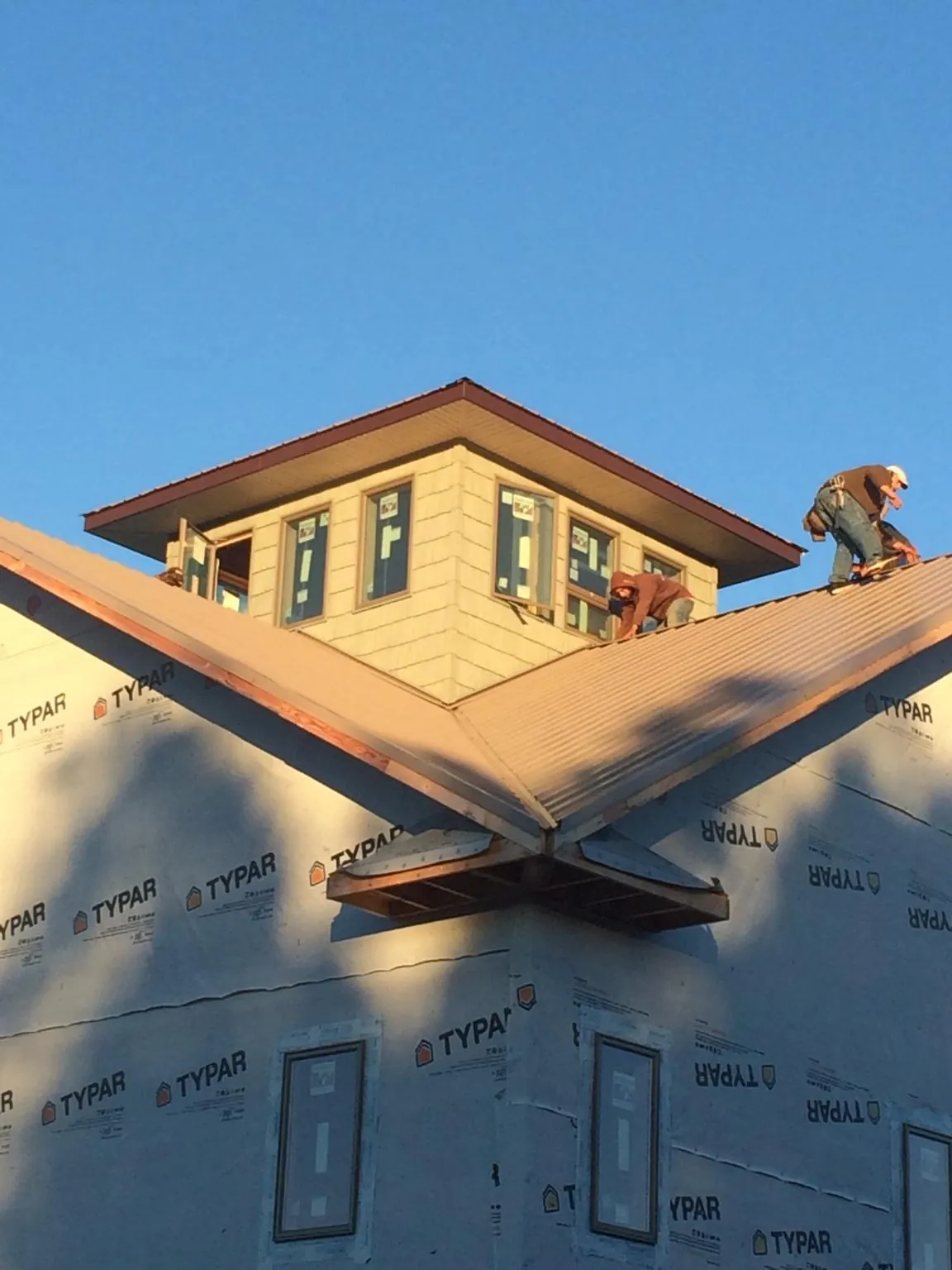 Roofers working around a rooftop cupola on a new metal roof at sunset — Roof Waterproofing in Winooski by Roofing Brothers